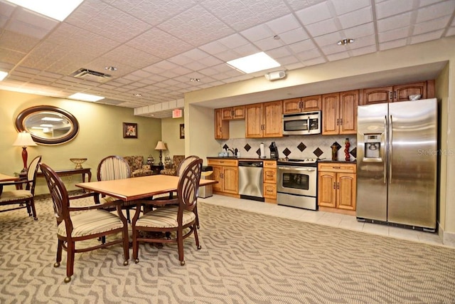 kitchen featuring decorative backsplash, a drop ceiling, light tile patterned flooring, and appliances with stainless steel finishes