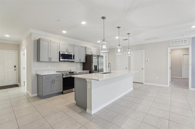 kitchen with gray cabinets, ornamental molding, a kitchen island with sink, and appliances with stainless steel finishes