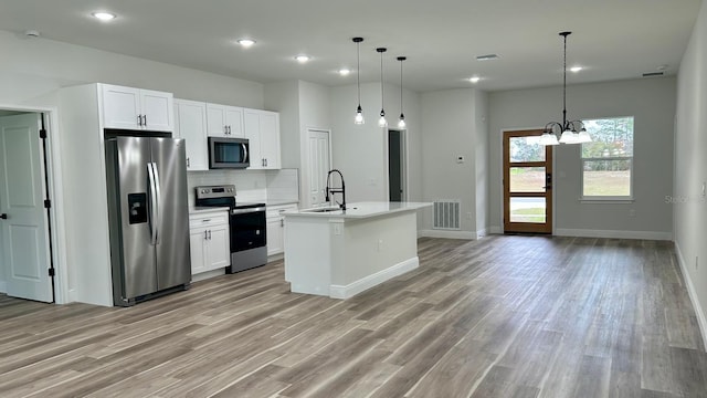 kitchen featuring pendant lighting, a center island with sink, white cabinets, appliances with stainless steel finishes, and a chandelier