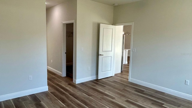 unfurnished bedroom featuring a walk in closet, dark hardwood / wood-style floors, and a closet