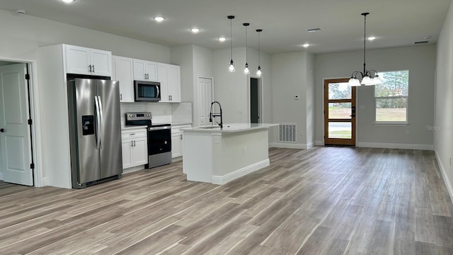 kitchen with light wood-type flooring, tasteful backsplash, visible vents, and stainless steel appliances