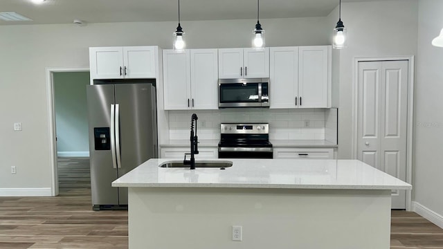 kitchen with white cabinets, decorative backsplash, appliances with stainless steel finishes, wood finished floors, and a sink