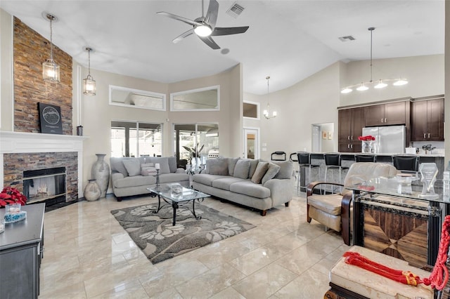 living room with a fireplace, high vaulted ceiling, and ceiling fan with notable chandelier