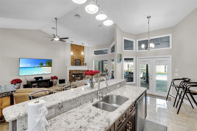 kitchen with french doors, a stone fireplace, sink, decorative light fixtures, and dishwasher