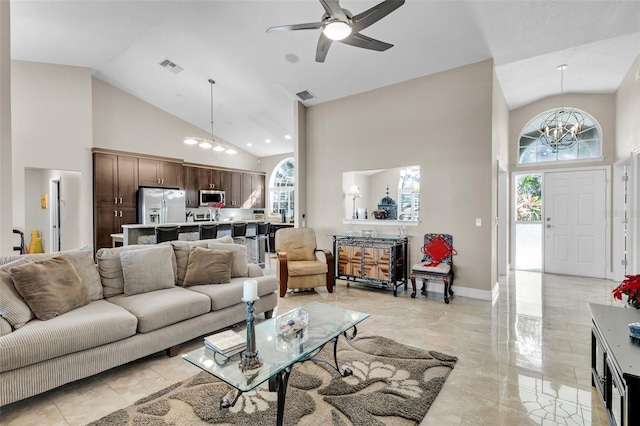 living room with ceiling fan with notable chandelier and high vaulted ceiling