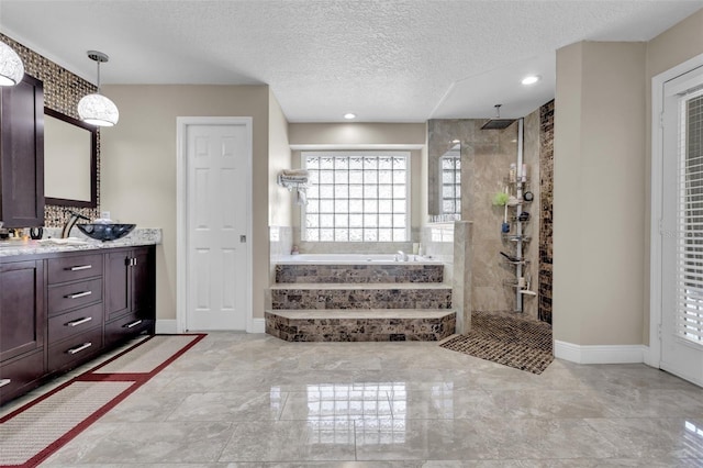 bathroom featuring independent shower and bath, vanity, and a textured ceiling