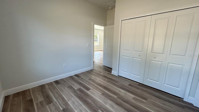 unfurnished bedroom with dark hardwood / wood-style flooring and a closet