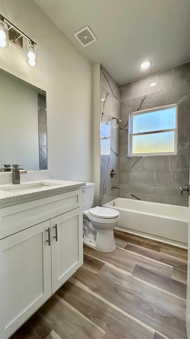 full bathroom with vanity, hardwood / wood-style flooring, toilet, and tiled shower / bath