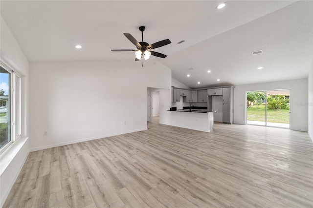 unfurnished living room featuring light hardwood / wood-style floors, vaulted ceiling, ceiling fan, and sink