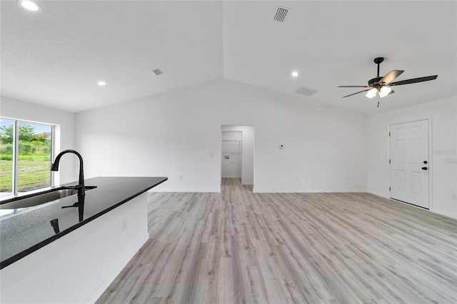 unfurnished living room with light hardwood / wood-style flooring, ceiling fan, lofted ceiling, and sink