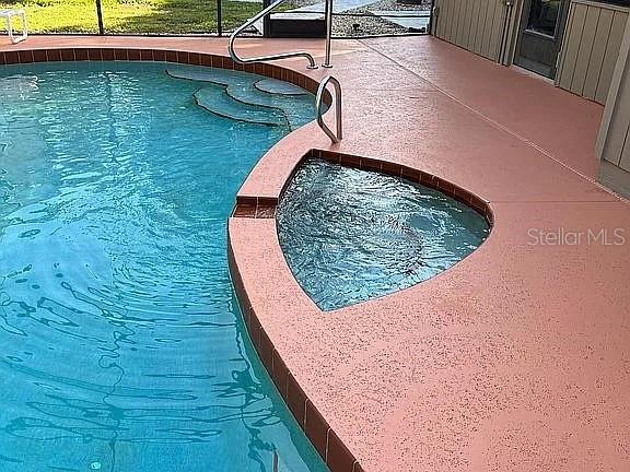 view of swimming pool with an in ground hot tub and a lanai