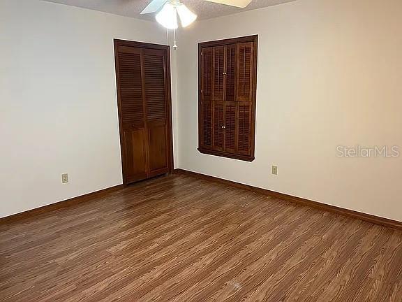 unfurnished bedroom featuring a textured ceiling, ceiling fan, and dark wood-type flooring