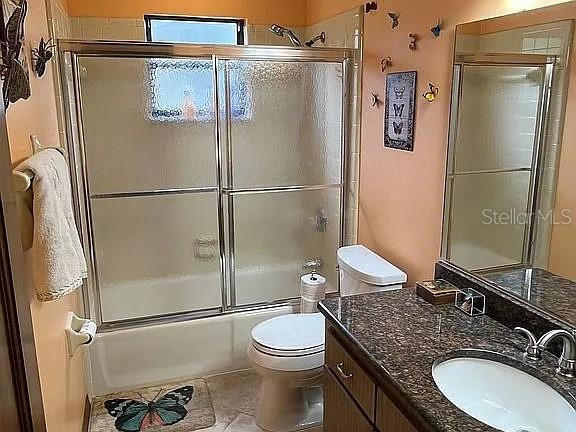 full bathroom featuring tile patterned flooring, vanity, toilet, and enclosed tub / shower combo