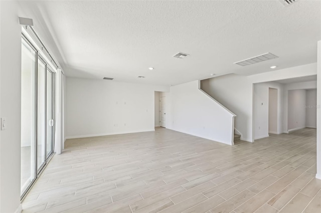 unfurnished living room with a textured ceiling and light wood-type flooring