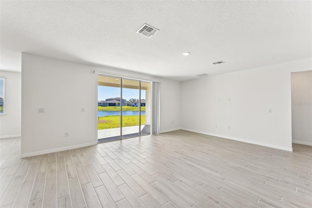 empty room with light hardwood / wood-style flooring and a water view