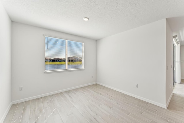 unfurnished room featuring light wood-type flooring and a textured ceiling