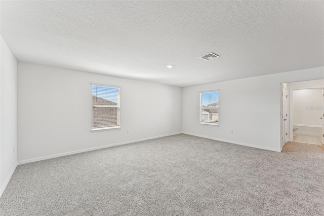 spare room with a textured ceiling and light carpet