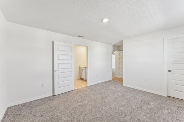 empty room featuring light colored carpet and a textured ceiling