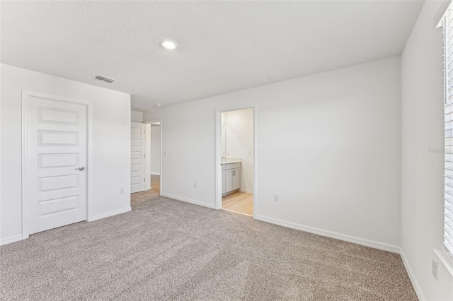 unfurnished bedroom featuring connected bathroom, a closet, and light carpet