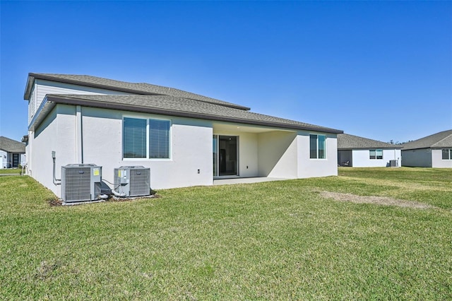 back of property with central air condition unit and a yard