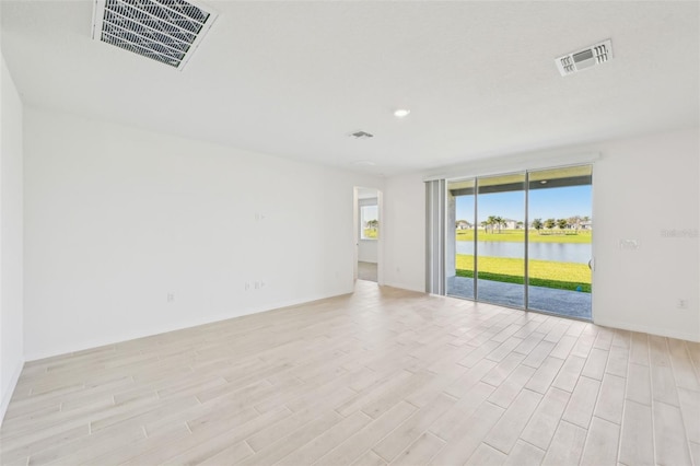 unfurnished room with visible vents, light wood-type flooring, and a water view