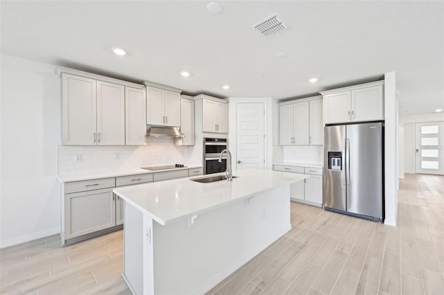 kitchen with visible vents, wood finish floors, a sink, stainless steel appliances, and under cabinet range hood