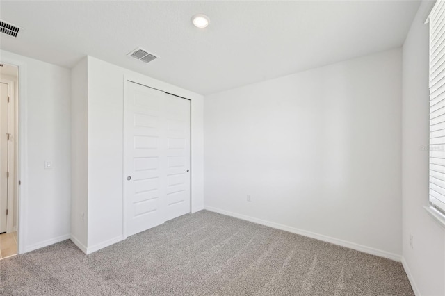 unfurnished bedroom with visible vents, light carpet, baseboards, and a closet