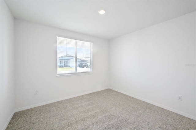 spare room with baseboards and carpet floors