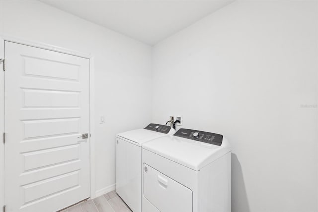 laundry area with laundry area, light wood-style flooring, washing machine and dryer, and baseboards