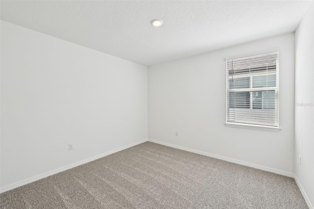 carpeted empty room with baseboards and a textured ceiling