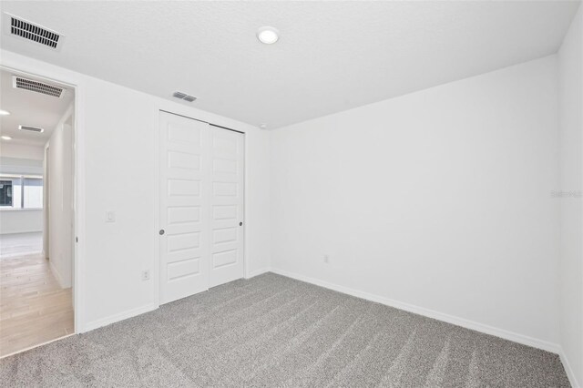 unfurnished bedroom featuring visible vents, baseboards, carpet, and a closet