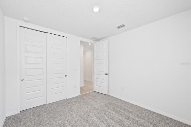 unfurnished bedroom with a closet, visible vents, baseboards, and carpet floors