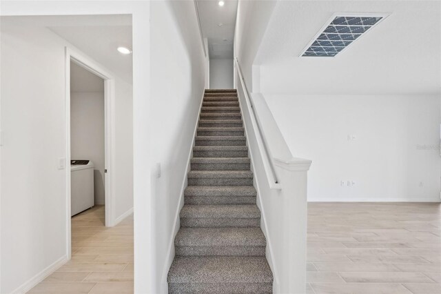 staircase featuring visible vents, baseboards, recessed lighting, washer / dryer, and wood finished floors