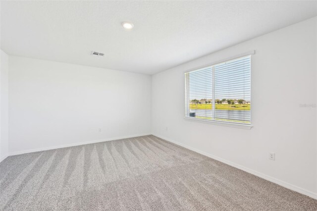 carpeted spare room with visible vents and baseboards