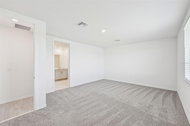 carpeted empty room featuring recessed lighting, visible vents, and baseboards