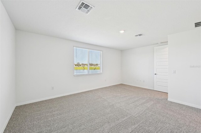 spare room with visible vents, baseboards, and carpet flooring