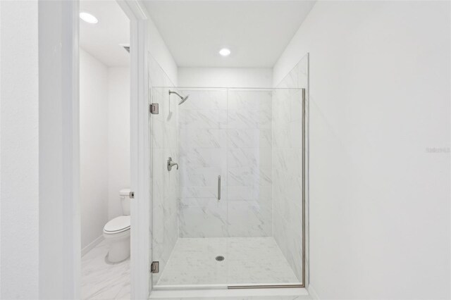 bathroom with toilet, baseboards, marble finish floor, and a marble finish shower