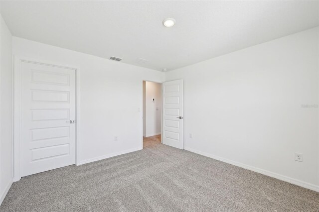 carpeted spare room with baseboards and visible vents