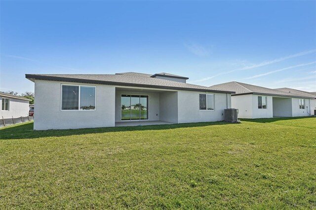 back of house with cooling unit, a yard, and stucco siding