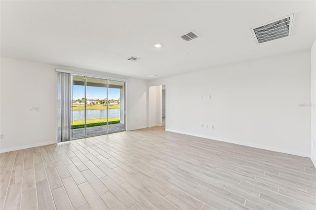 empty room with light hardwood / wood-style floors and a water view