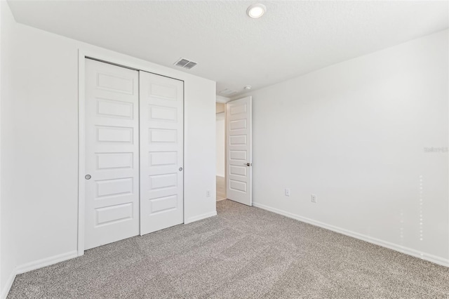 unfurnished bedroom with a textured ceiling, a closet, and carpet