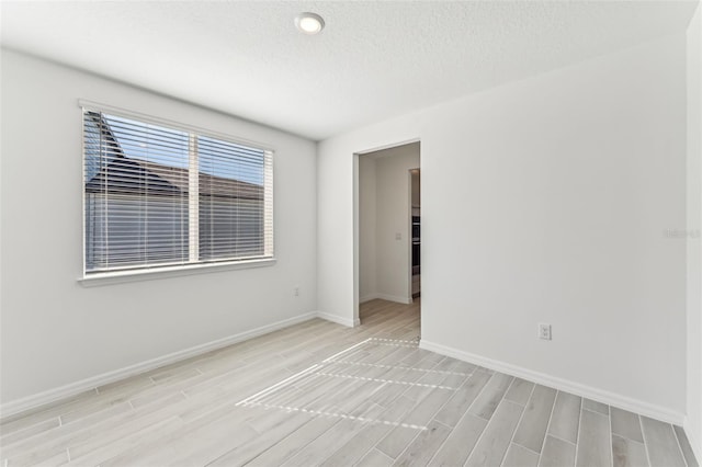 spare room featuring a textured ceiling and light hardwood / wood-style flooring