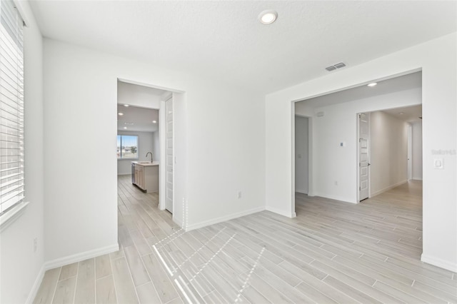 spare room with sink and light hardwood / wood-style floors