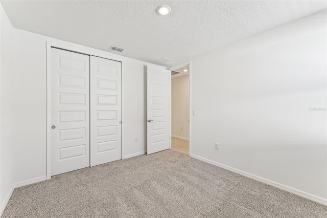 unfurnished bedroom with a textured ceiling, carpet floors, and a closet