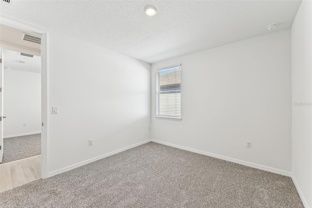 unfurnished room featuring a textured ceiling and light colored carpet