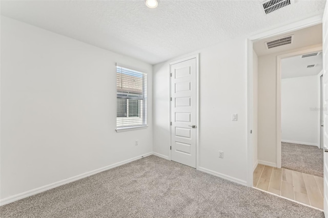 unfurnished bedroom featuring a textured ceiling and light carpet