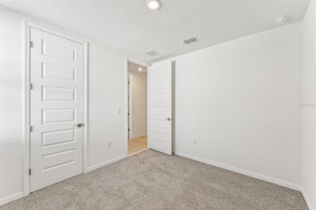 unfurnished bedroom with a textured ceiling and light colored carpet