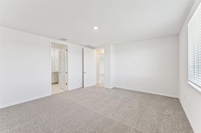 unfurnished bedroom featuring connected bathroom and light colored carpet