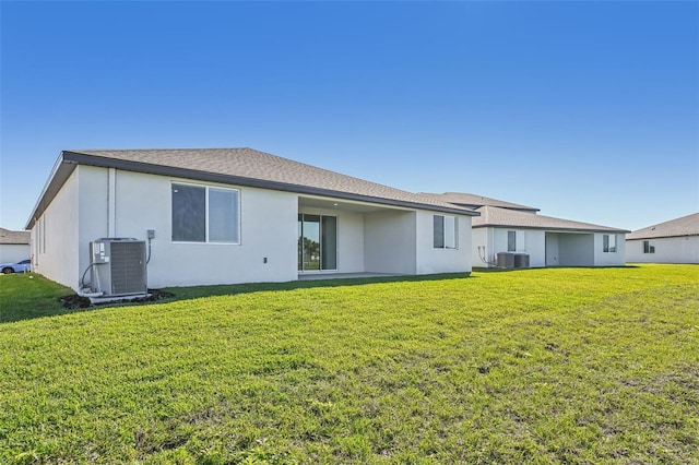 rear view of house featuring central air condition unit and a lawn