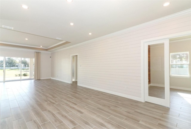 unfurnished room with wooden walls, crown molding, and light wood-type flooring